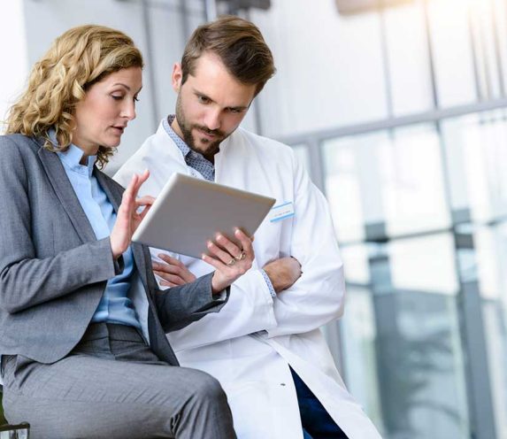 Businesswoman with tablet and doctor talking in hospital