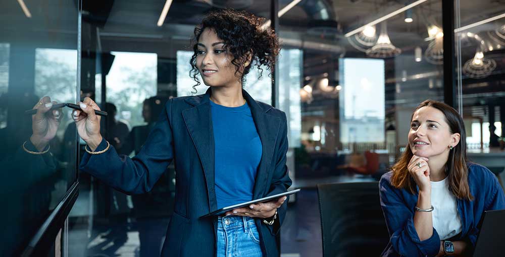 Stay on Top of Trends with Market Research to Make Decision and Setting Goal of Your Business. A female marketeer is on a presenting a market data on a digital display to make decision for new products launch with her team in a business office